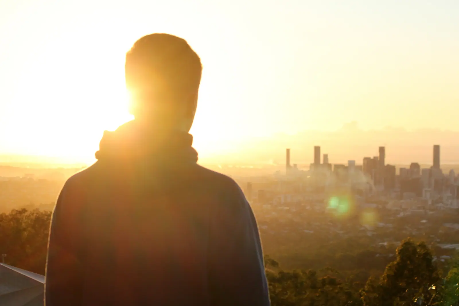 Man looking out over a city at sunrise while exploring Anthem rehab coverage