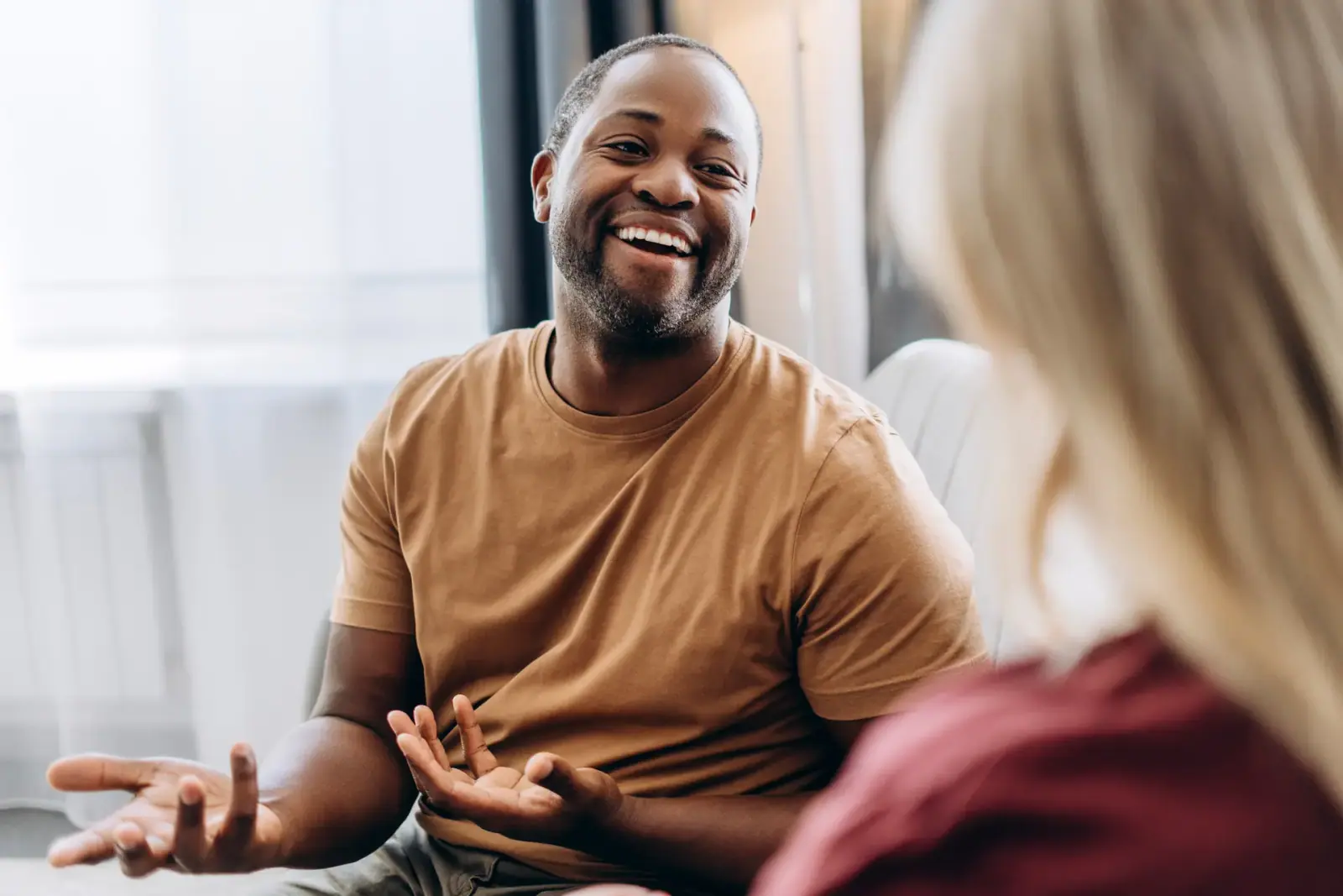 Smiling man gesturing during a friendly indoor conversation about MultiPlan benefits
