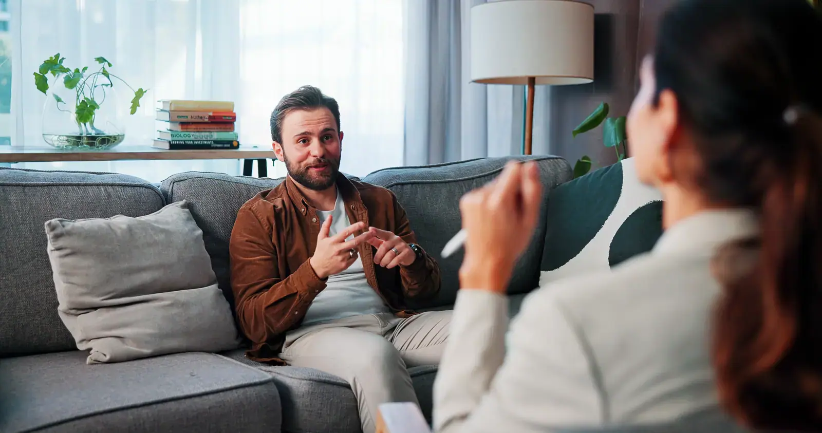 Man in a brown shirt speaking with a counselor taking notes during a private session