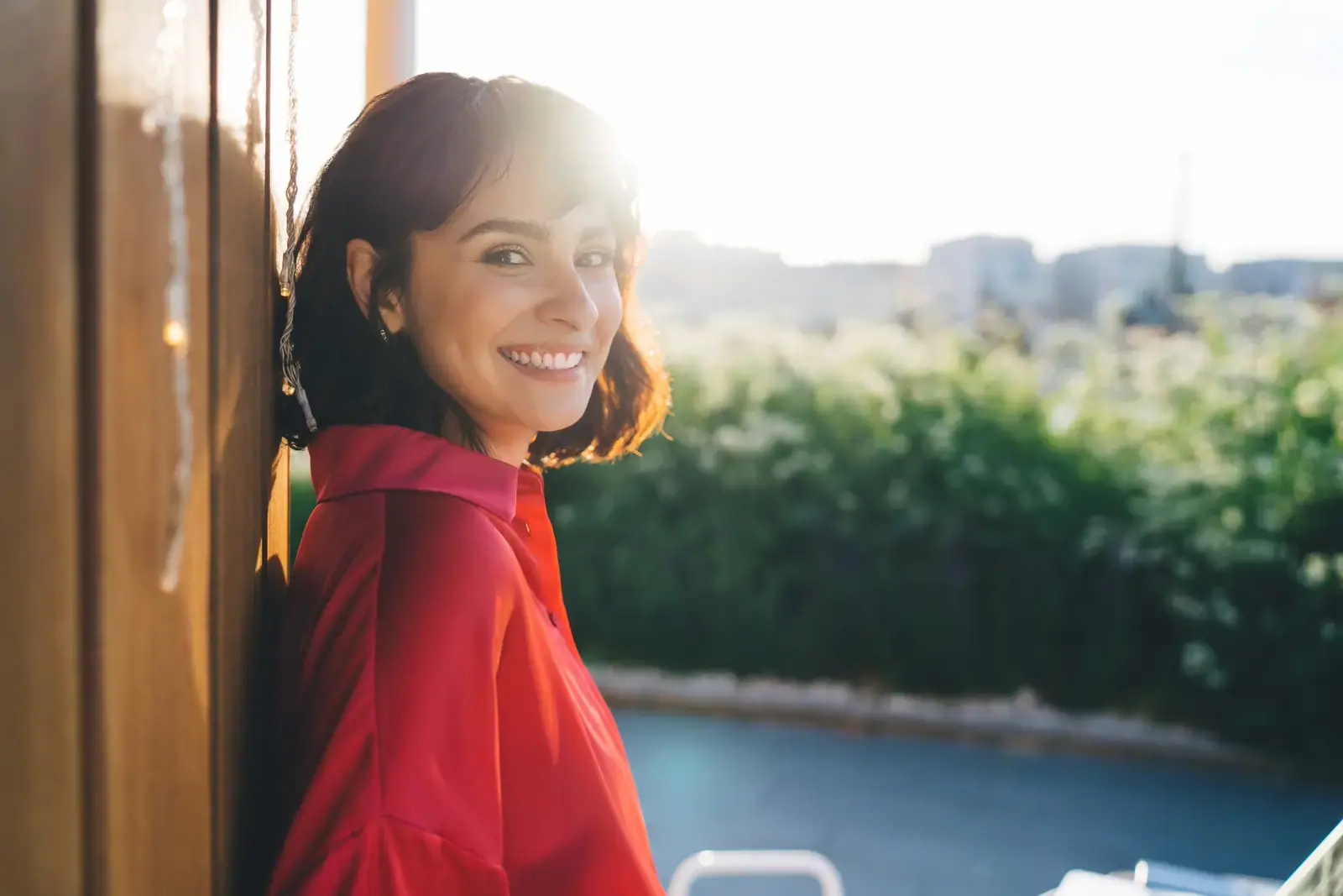 Woman in a red top looking out at a warm sunset