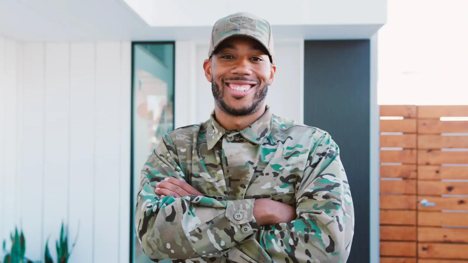 Smiling man in camouflage clothing standing outside a house