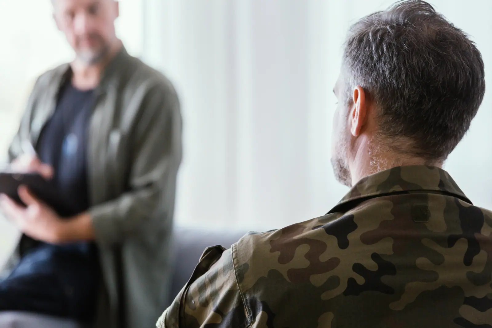 Man in a camouflage shirt talking with a counselor