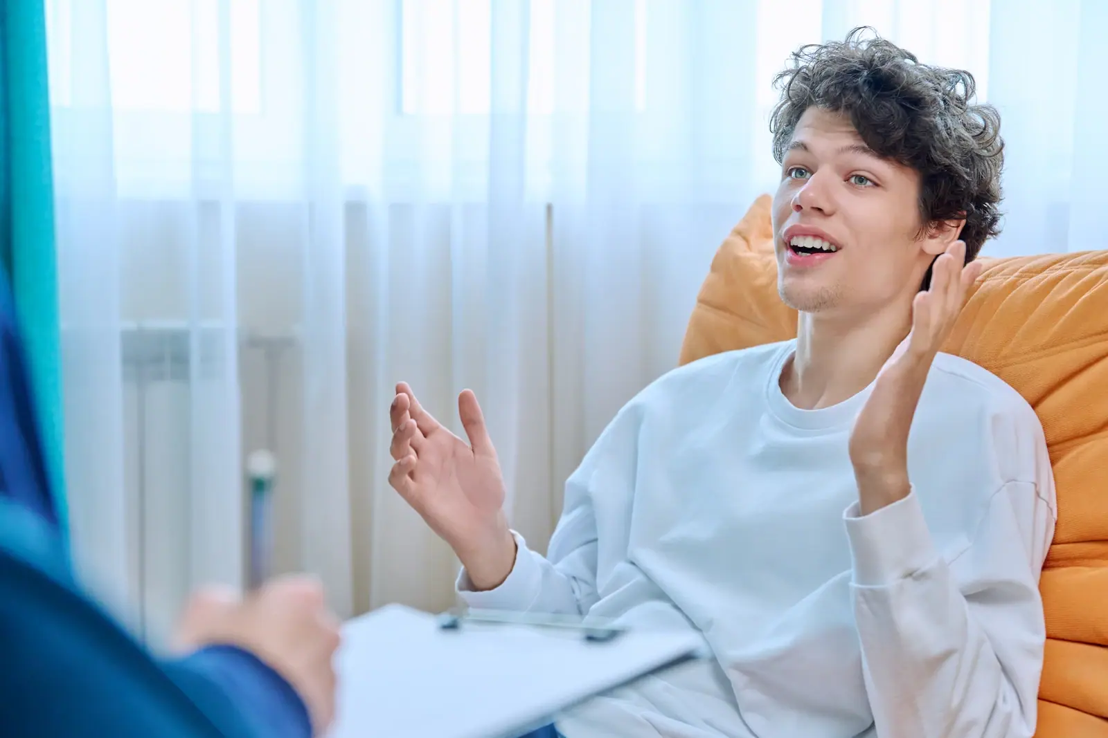 Young man gesturing while talking with someone indoors