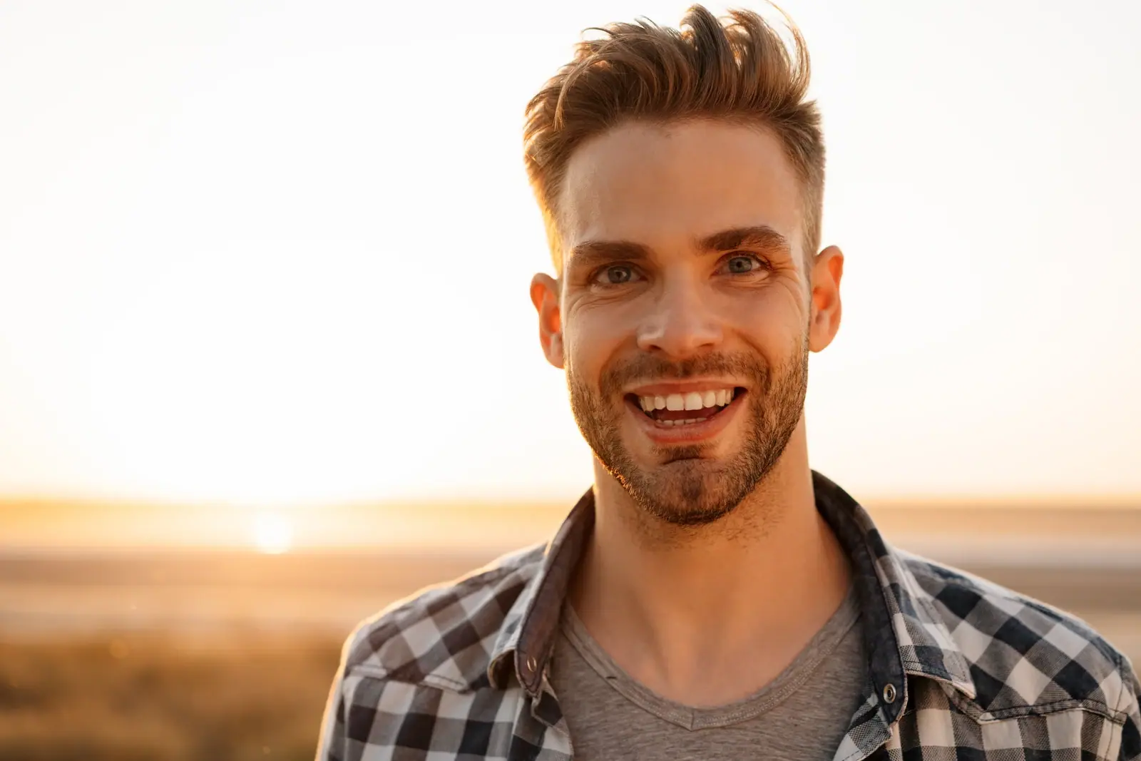 Smiling bearded man outdoors in golden sunset light